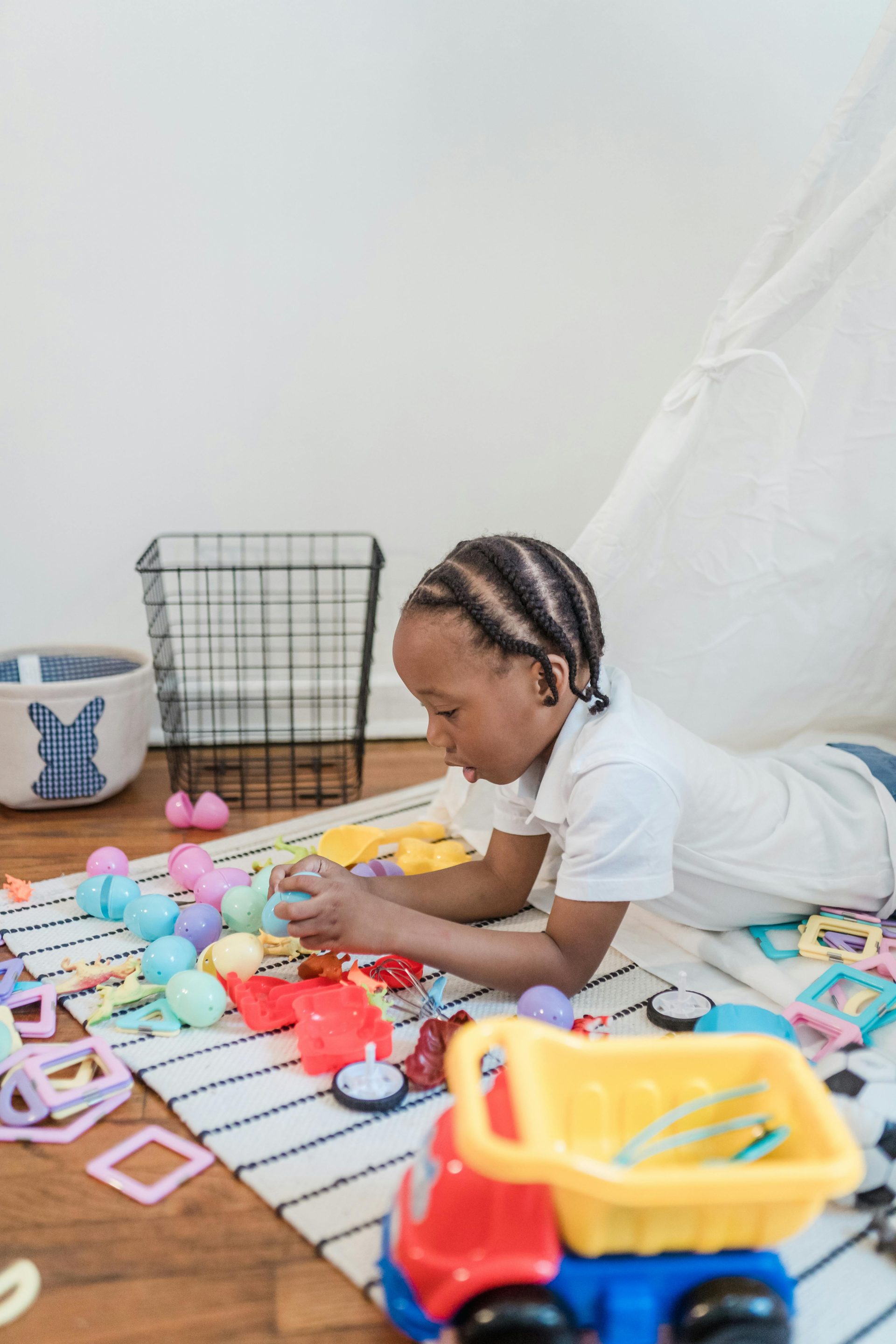 Joyful child playing with colorful toys indoors on a striped rug, expressing happiness and creativity.