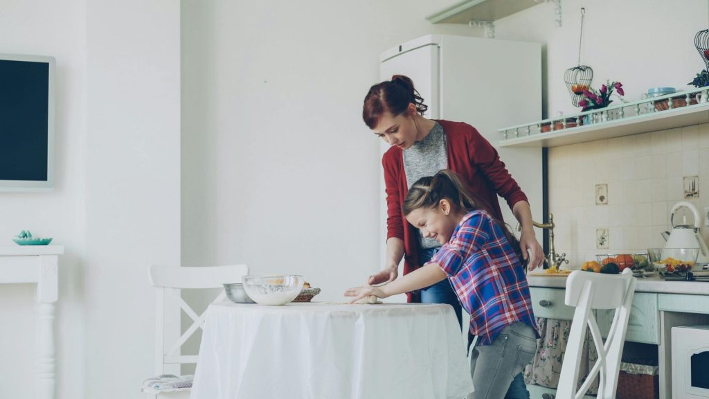 A mother and daughter bonding while baking together in a comfortable kitchen setting.