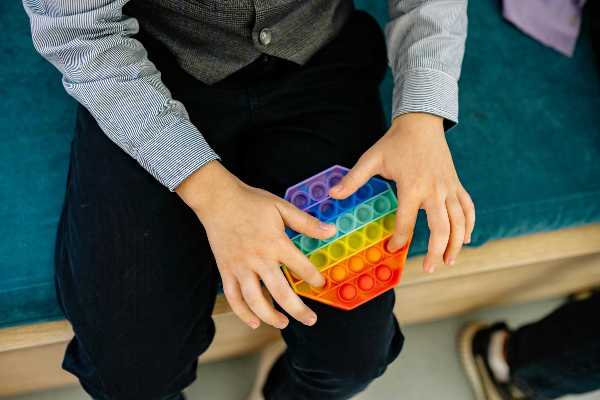A child's hands engaging with a rainbow pop it fidget toy, promoting sensory play.
